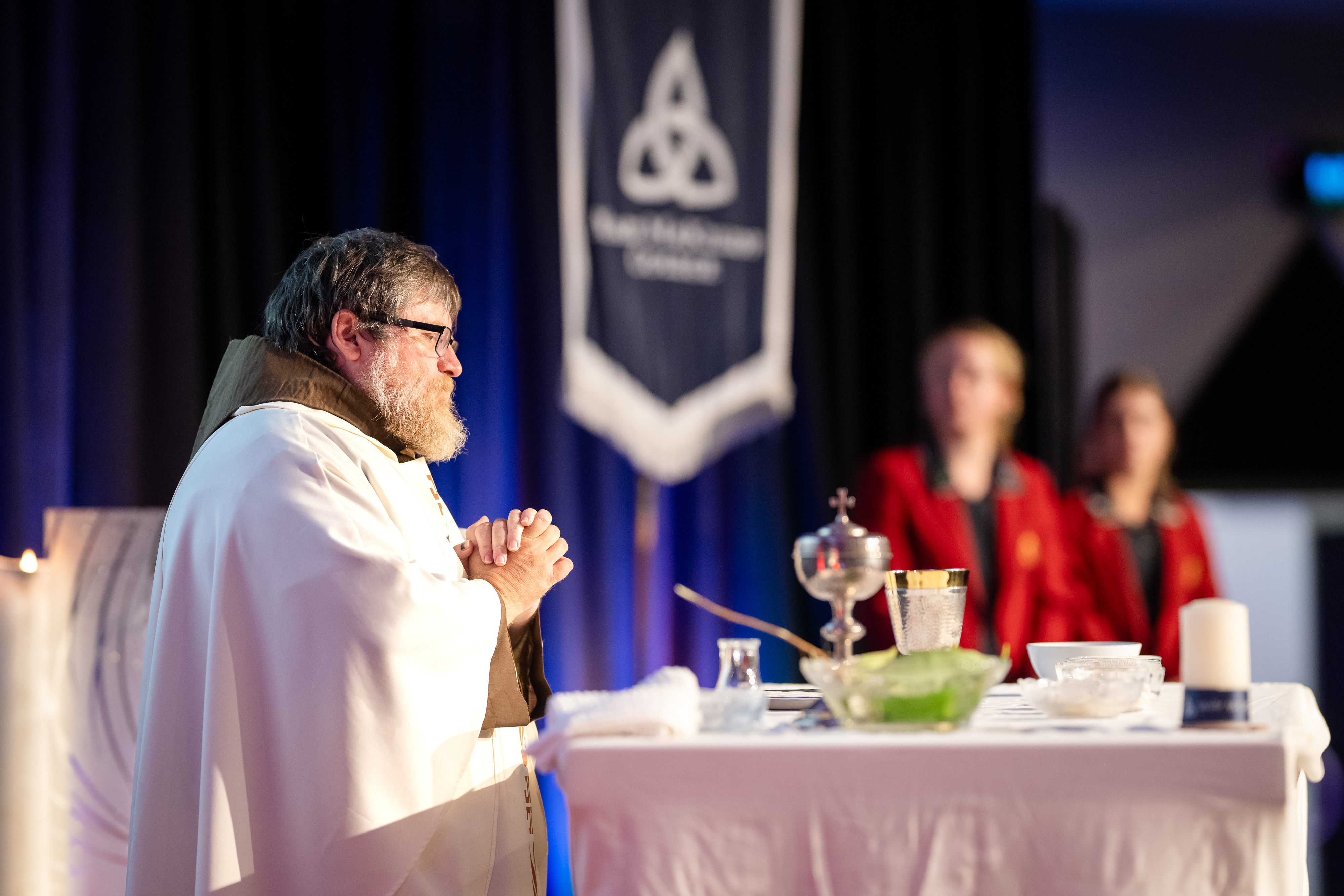 Priest standing at an altar with communion vessels during a school liturgy