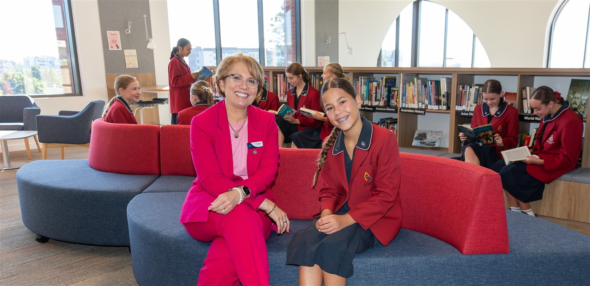 Principal Erin Wedge sitting with a student in the Library.
