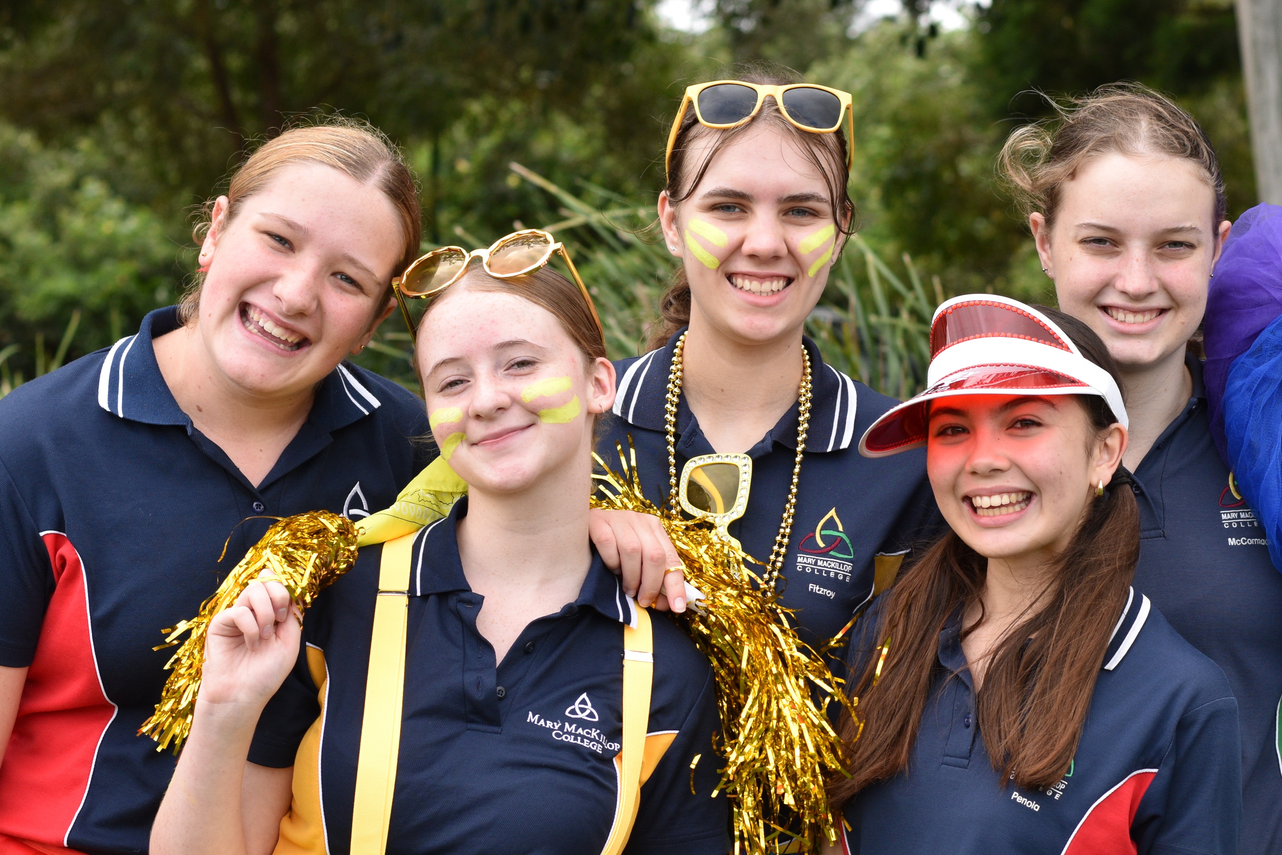 Group of students in school uniforms standing together outdoors wearing face paint and accessories during a school event