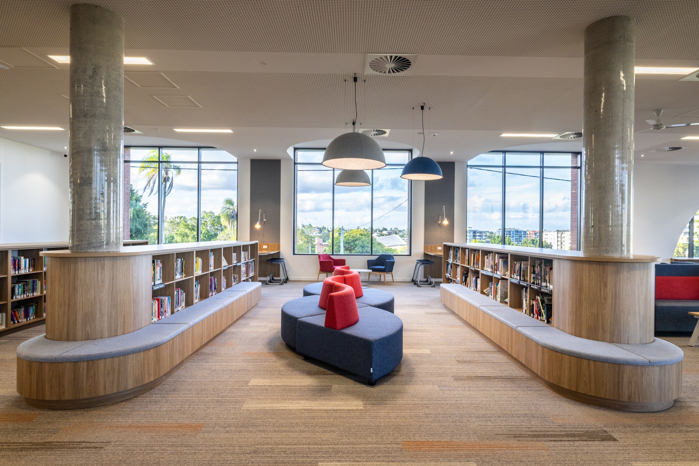 School library interior with low bookshelves, curved seating and large arched windows